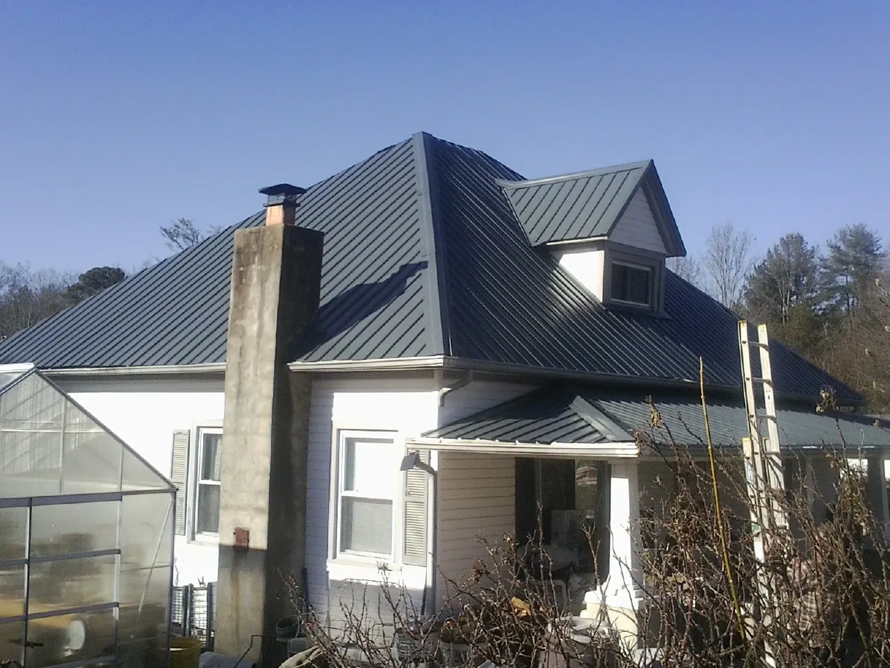 Dark blue standing seam metal roof on a white farmhouse with dormer — Slate & Tile Roof Repair by Roofing Brothers in Bayview