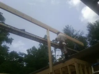Carpenter setting a ridge beam over a new addition frame — Ice Dam Removal by Roofing Brothers in Bayview