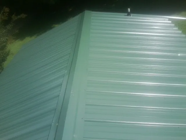 New green metal panels meeting at the ridge of a roof — Flat Roof Repair work by our crew in Bayview