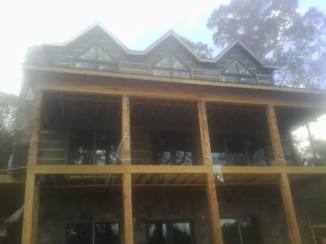 Dormers and porch framing on a large log home under construction — Roof Coating work by our crew in Bayview