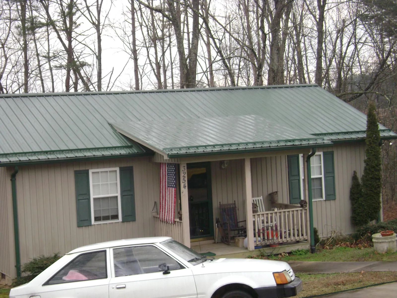 Green metal roof and front porch on a tan sided cottage in Bayview
