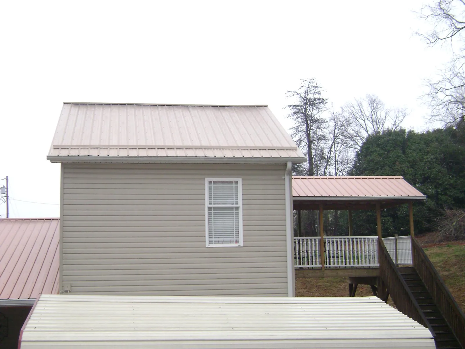Tan metal roofs on a two story addition and attached porch, from a Roof Replacement job in Bayview