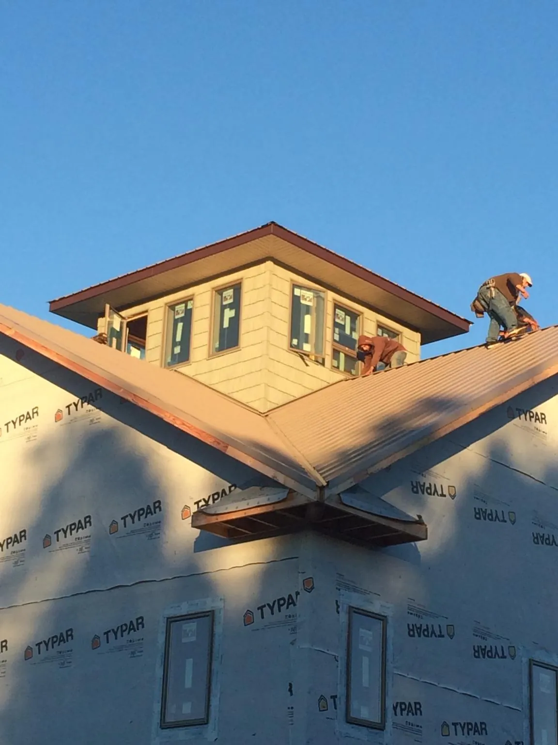 Roofers working around a rooftop cupola on a new metal roof at sunset — Roof Waterproofing in Bayview by Roofing Brothers